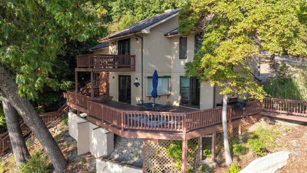 Ein zweistöckiges Haus mit einer Terrasse, umgeben von Bäumen.