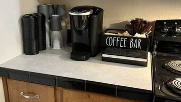 Een keuken met houten kastjes, een koffiezetapparaat en een bord met daarop 'Koffiebar'.