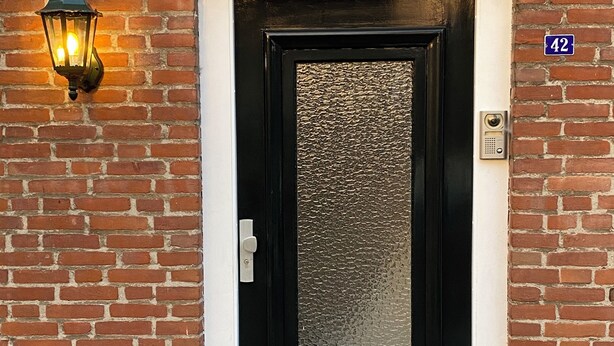 A black door with a textured glass panel, a small window above it, and a number plate '42' on the wall. - Right in the center across from the stores  (Udenhout)
