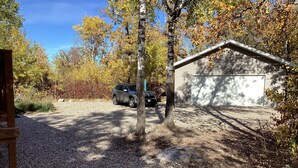 Une allée de gravier mène à un garage où un véhicule est garé à proximité.