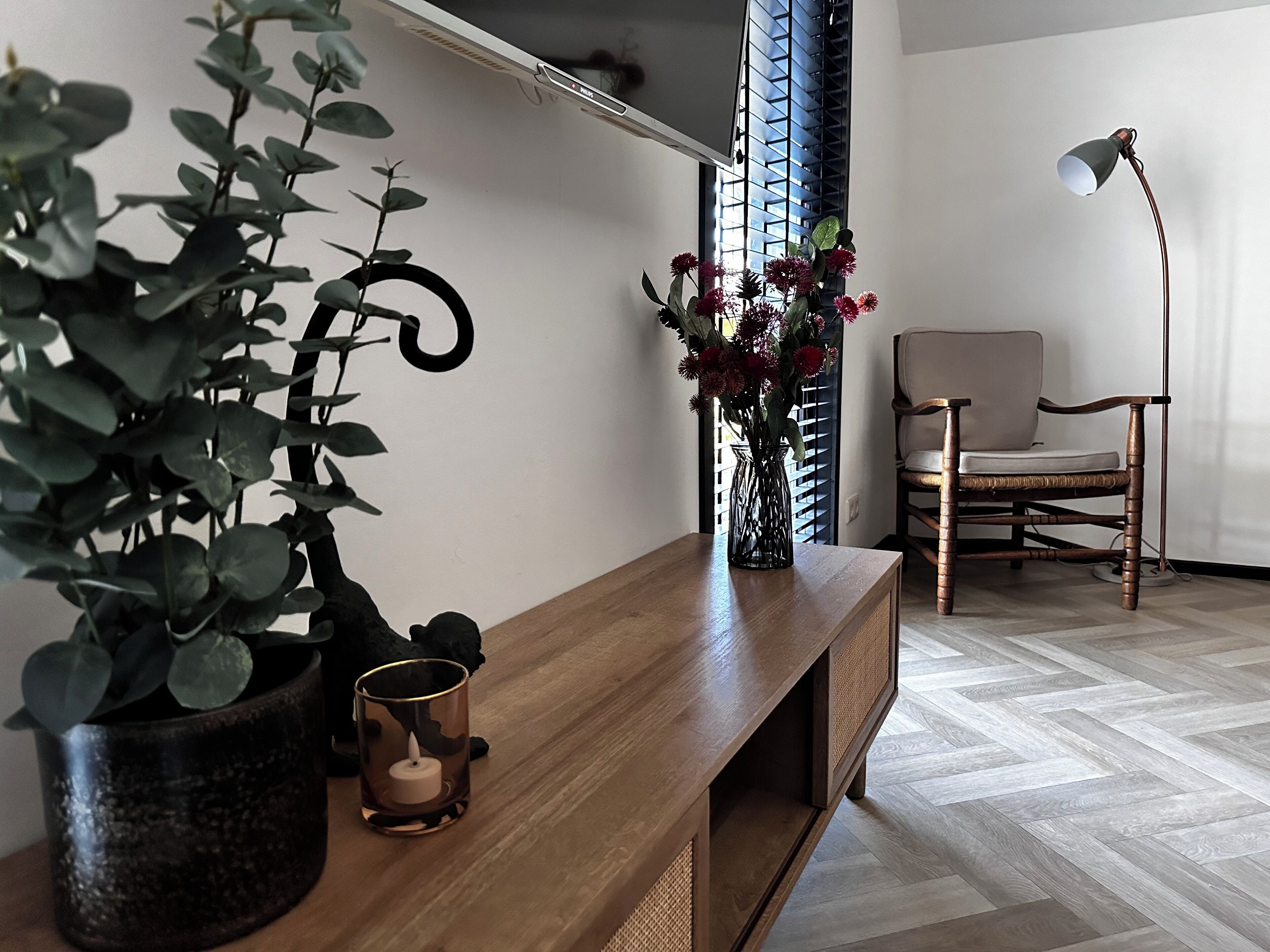 Ein Holzkonsolentisch mit Blumentopf, Blumen in einer Vase und einem Kerzenhalter.