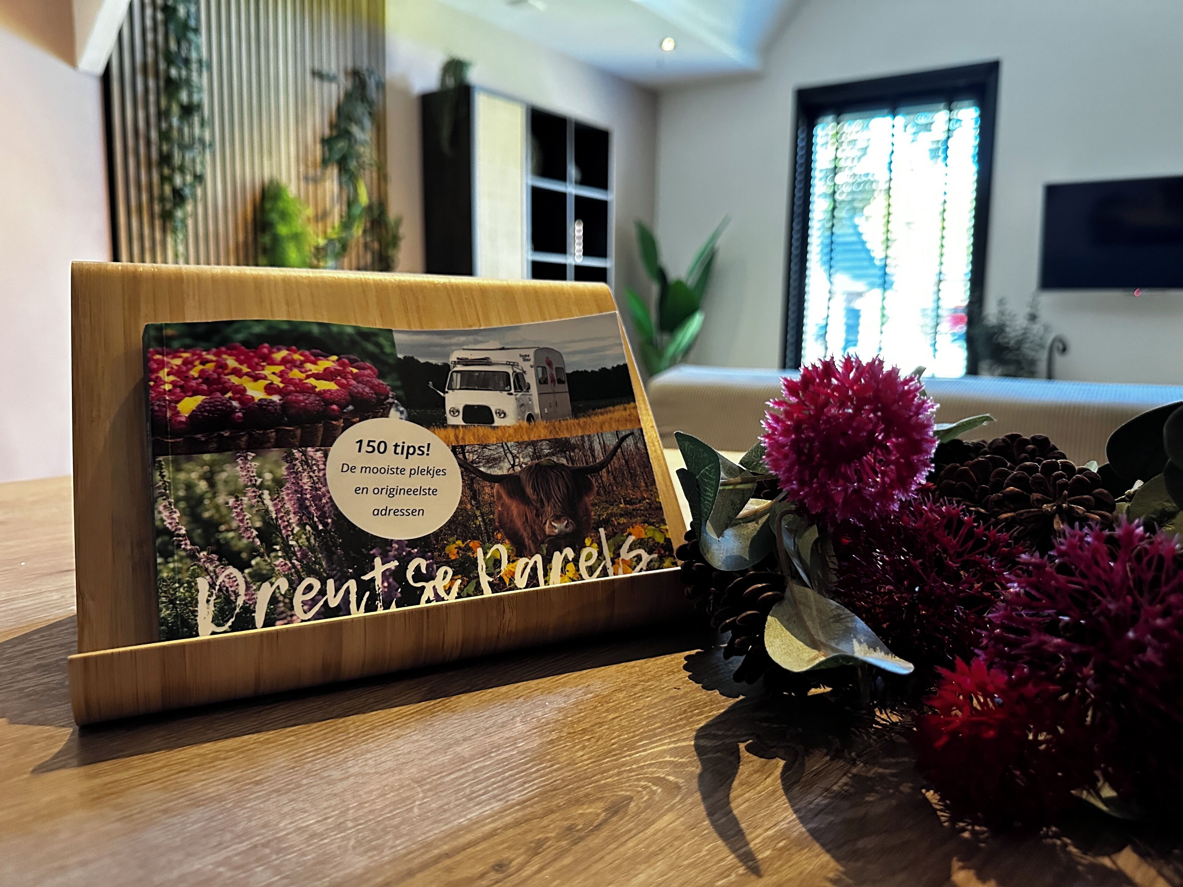 A book titled 'Creatse Se Pales' on a wooden table with decorative flowers and a window in the background.