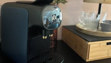 Een zwarte Philips koffiezetapparaat op een zwart aanrecht, met een houten bijzettafeltje en een vaas met roze en witte bloemen op de achtergrond.