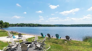 A lakeside setting with Adirondack chairs, a picnic table, and a fire pit. - The Lake Life by Avantstay Lakefront + View + Hot Tub (Pocono Lake)