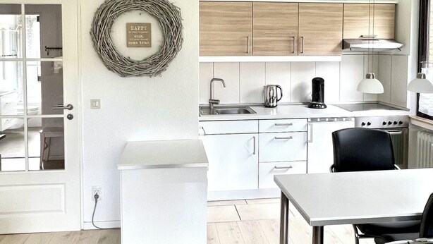 A modern kitchen with white cabinets, a stainless steel sink, and a coffee maker.