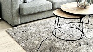 A modern living room with a grey sofa, two decorative pillows, a round coffee table, and a large elk painting on the wall.