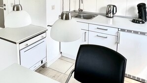 A modern kitchen with white cabinetry, a built-in oven, a sink, and a coffee maker.