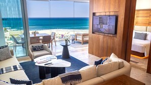 Een moderne hotelkamer met een ruim balkon met uitzicht op zee, een comfortabele zithoek en een wandtelevisie.