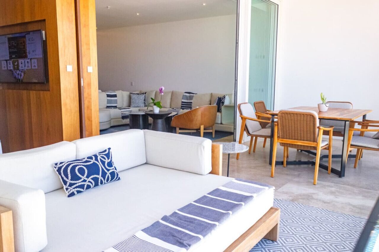 Ein modernes Wohnzimmer mit einem weißen Sofa, einem kleinen runden Tisch und einem Essbereich mit Holzsesseln und einem Tisch.
