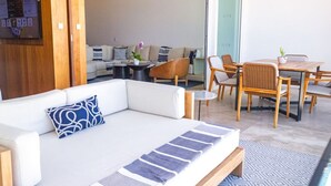 Een moderne woonkamer met een witte bank, een kleine ronde tafel en een eethoek met houten stoelen en een tafel.