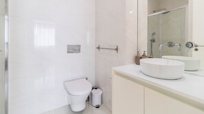 Ein modernes Badezimmer mit Toilette, Bidet und einem großen Spiegel über einem Waschbecken.