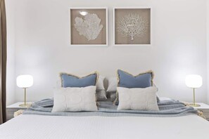 A neatly made bed with two pillows, a bedside lamp, and a framed artwork on the wall.