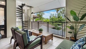 A balcony with a view of greenery, a wooden table, chairs, and a potted plant. - Rooftop Tranquility at Stunning Temple Resort (Craiglie)