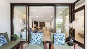 A modern living room with a sofa and chairs, a dining area, and a kitchen visible through glass doors. - Rooftop Tranquility at Stunning Temple Resort (Craiglie)