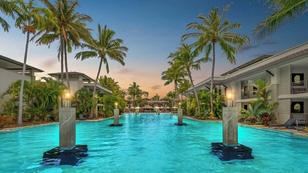 A swimming pool with palm trees and hotel buildings in the background. - Rooftop Tranquility at Stunning Temple Resort (Craiglie)