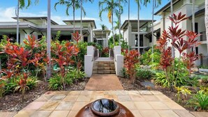 A modern resort with a central pathway leading to a staircase, surrounded by lush tropical plants and palm trees. - Rooftop Tranquility at Stunning Temple Resort (Craiglie)