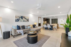 A modern living room with a sofa, coffee table, and dining area.