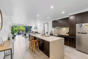 A modern kitchen with a central island, dark cabinets, and stainless steel appliances.