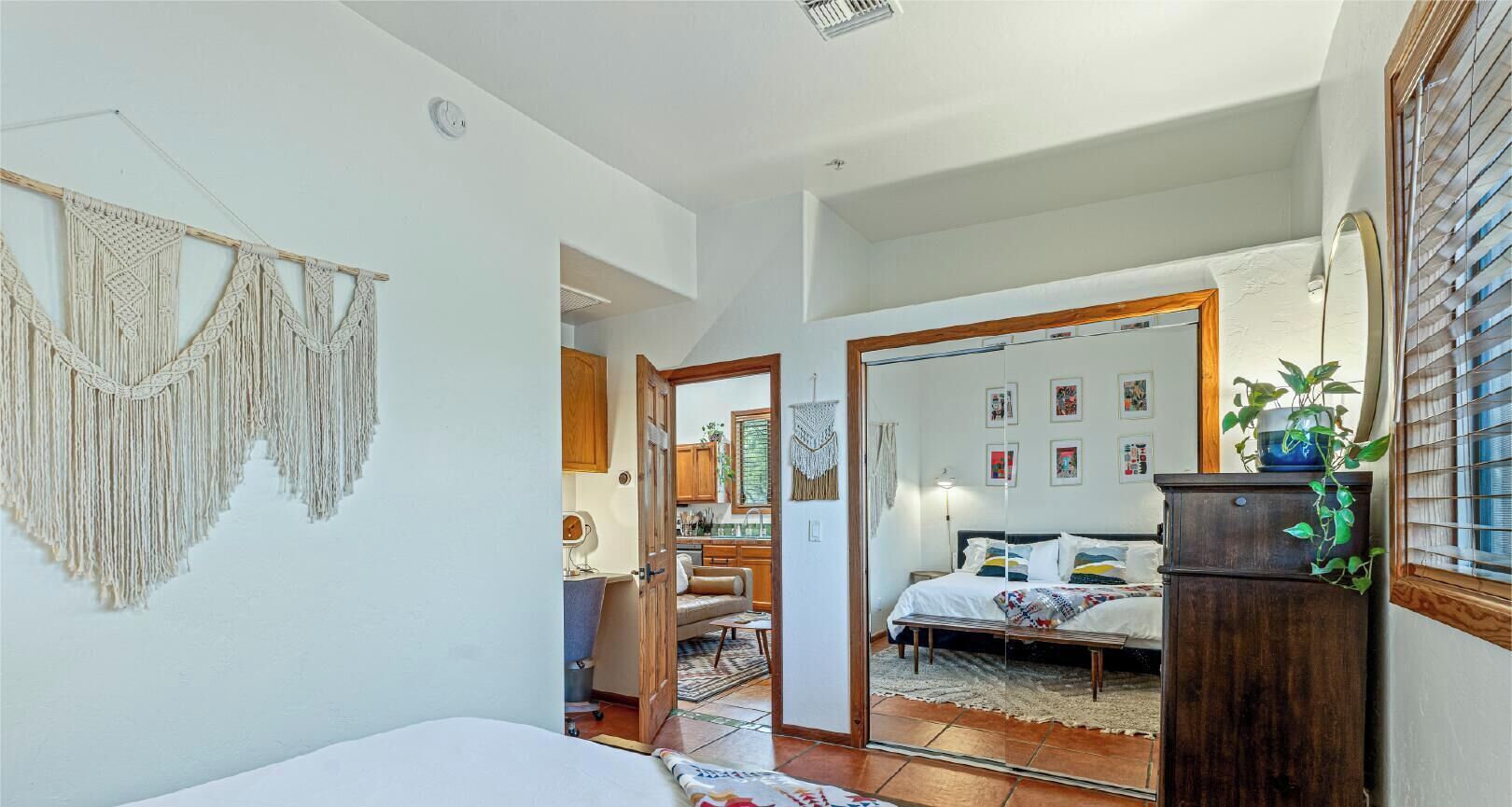 Une chambre à coucher avec un lit, une table de chevet, un miroir et une armoire.