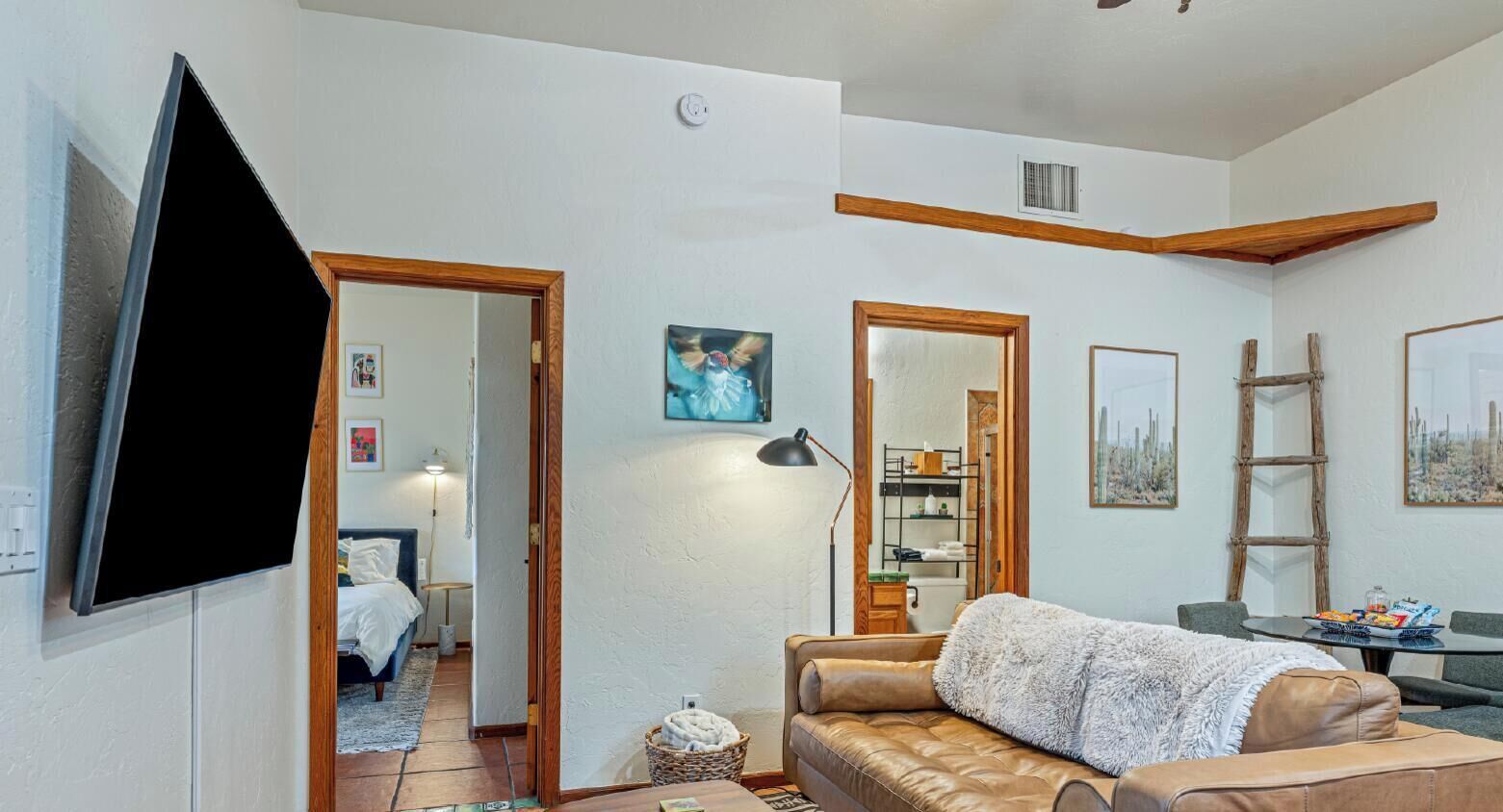 A living room with a sofa, a television, and a painting on the wall.