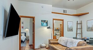 A living room with a sofa, a television, and a painting on the wall. - King Bed, Location, Pool, Fire Pit, & Views (Tucson)