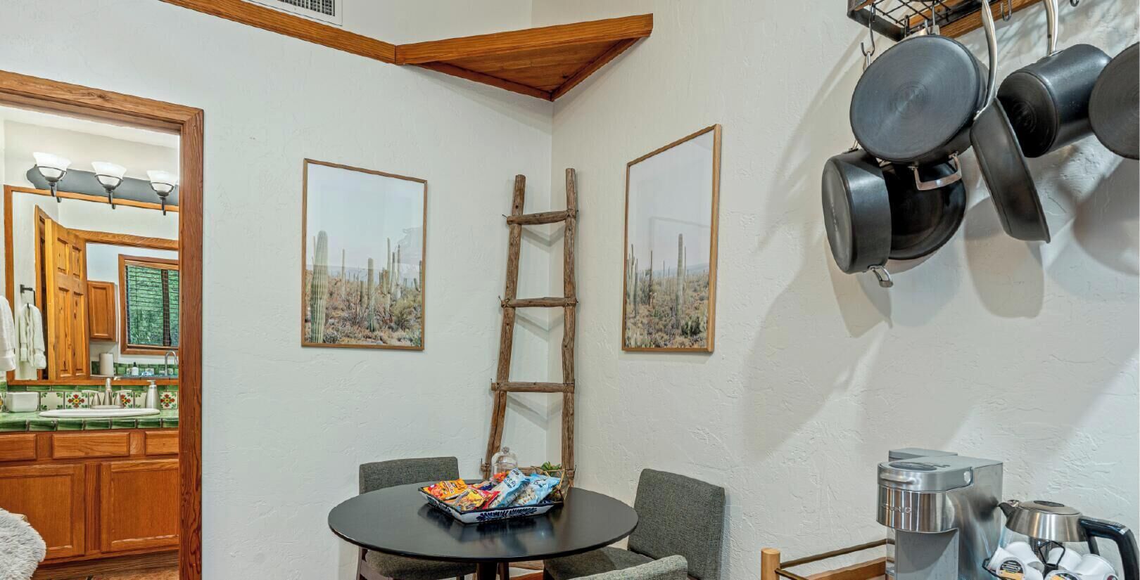 Une cuisine avec des meubles de rangement en bois, une table de salle à manger ronde entourée de chaises et une échelle appuyée contre le mur.