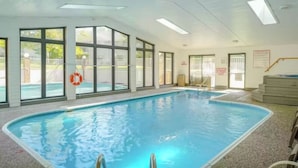 Une piscine intérieure avec des parois en verre transparent, une bouée de sauvetage et un escalier menant à un niveau supérieur.