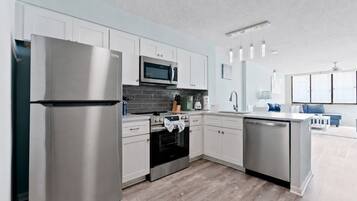 Una cocina moderna con electrodomésticos de acero inoxidable, armarios blancos y un salpicadero de azulejos grises.