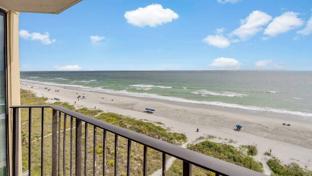 A balcony with a view of a beach and ocean.
