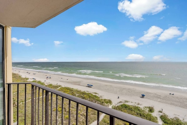 Un balcon avec vue sur une plage et l’océan.