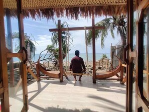 A person sitting on a wooden swing chair facing a beach with palm trees and a clear sky. - Shurjo Snan Twin Beach Resort (Saint Martin's Island)