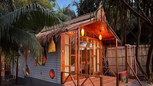 A wooden house with a thatched roof, a porch, and a small deck. - Shurjo Snan Twin Beach Resort (Saint Martin's Island)