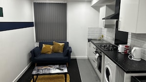 A compact kitchen with a sofa, washing machine, and a coffee maker. - London Road Studio Retreat in Leicester (Leicester)