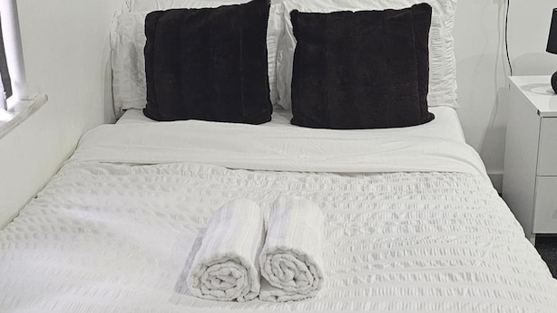 A neatly made bed with white bedding and two dark pillows. - London Road Studio Retreat in Leicester (Leicester)
