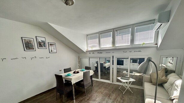 Un espace de vie et de salle à manger moderne, à plan ouvert, doté d’un haut plafond et de grandes fenêtres.