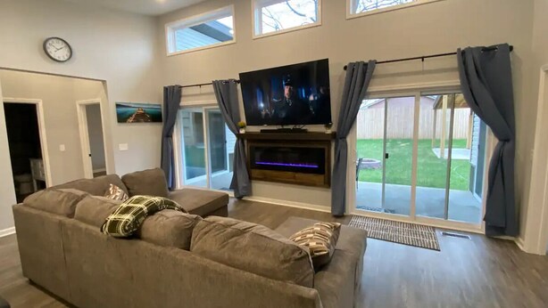 Un salón espacioso con una gran televisión de pantalla plana, un sofá cómodo y un ventanal corredero que da a un jardín.
