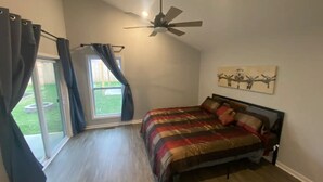 Un dormitorio con cama, ventilador de techo y ventana con cortinas.
