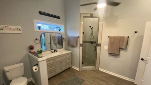 Un baño con inodoro, lavamanos, tocador, ducha y ventilador de techo.