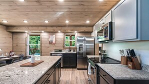 Una cocina moderna con encimeras de granito, electrodomésticos de acero inoxidable y armarios de madera.
