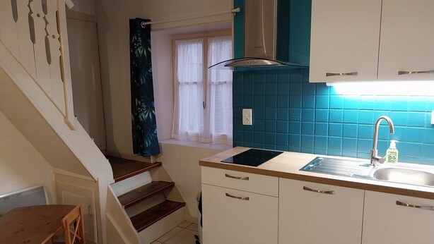Una cocina compacta con lavamanos, estufa y armarios blancos.