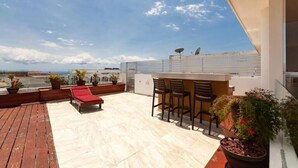 Une terrasse sur le toit comprenant un bar, des espaces pour s’asseoir et des plantes en pot.