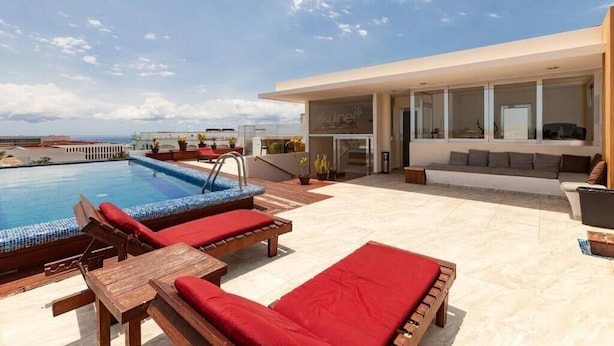 Un espace piscine extérieur moderne, doté de chaises longues et d’un coin salon.