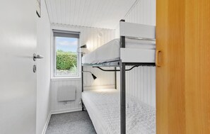 Une chambre avec un lit superposé, une fenêtre, une porte et un radiateur.