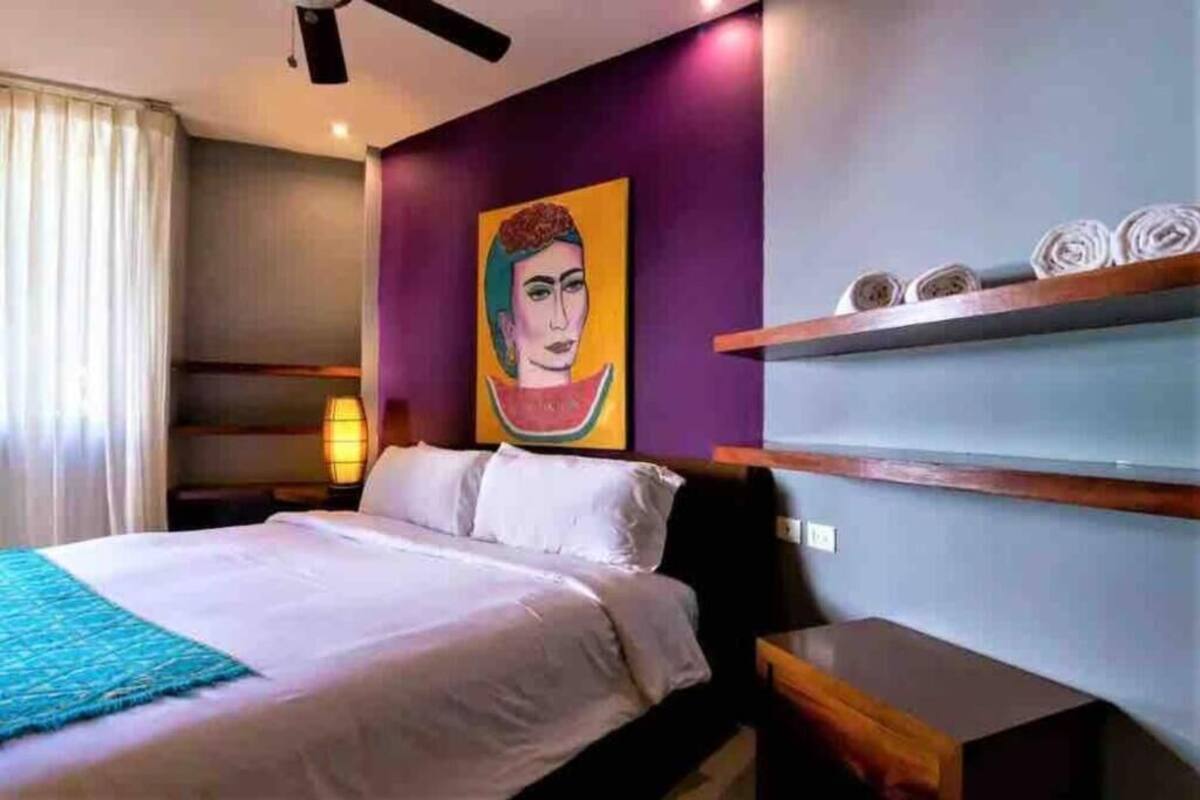 Une chambre d’hôtel avec un lit, un tableau au mur et une étagère où sont pliés des serviettes.