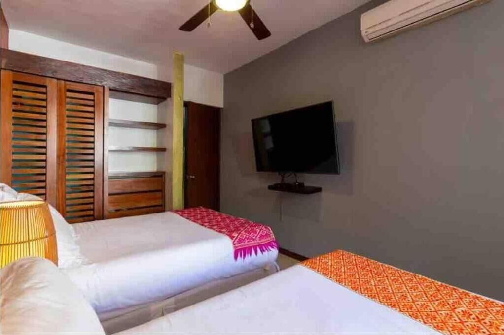 Habitación de hotel con dos camas, un televisor y un ventilador de techo.