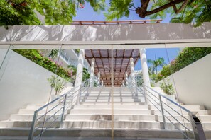 A staircase leading up to a covered area with a pergola, surrounded by greenery and a clear sky. - Magia by Zamá Homes (Playa del Carmen)