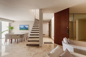 A modern interior with a staircase, dining area, and a living space with a sofa. - Magia by Zamá Homes (Playa del Carmen)