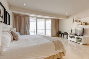 A modern bedroom with a large bed, a TV, and a desk. - Magia by Zamá Homes (Playa del Carmen)
