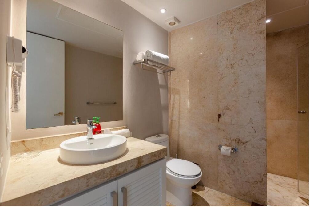 A modern bathroom with a marble sink, a toilet, and a shower area.