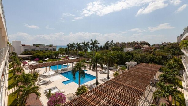 A resort with a swimming pool, palm trees, and a view of the ocean. - Magia by Zamá Homes (Playa del Carmen)
